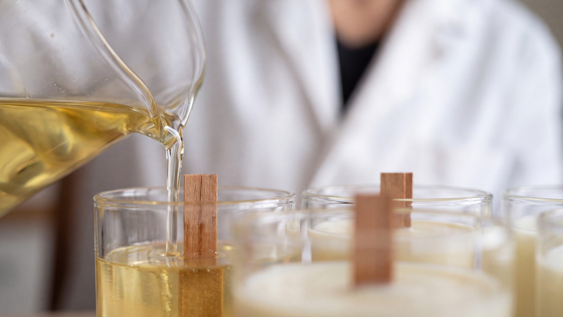 Cire végétale liquide versée dans des pots en verre à mèche de bois, atelier L&E